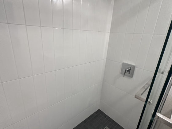 Modern walk-in shower with white subway tile walls and black textured floor